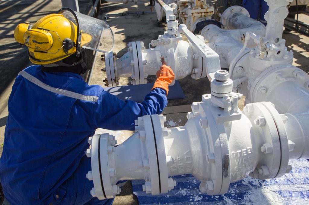 Male worker painted white at pipes and oil valve