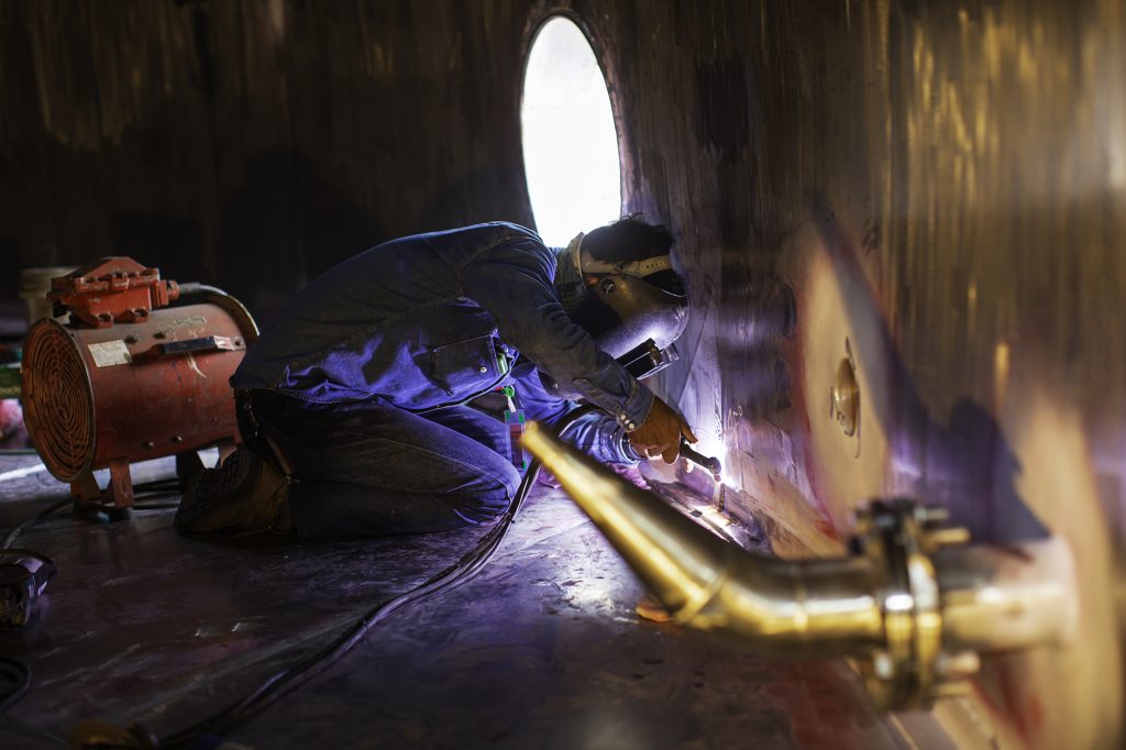 Welding  arc argon worker male repaired metal is welding sparks industrial construction tank stainless oil inside confined spaces.