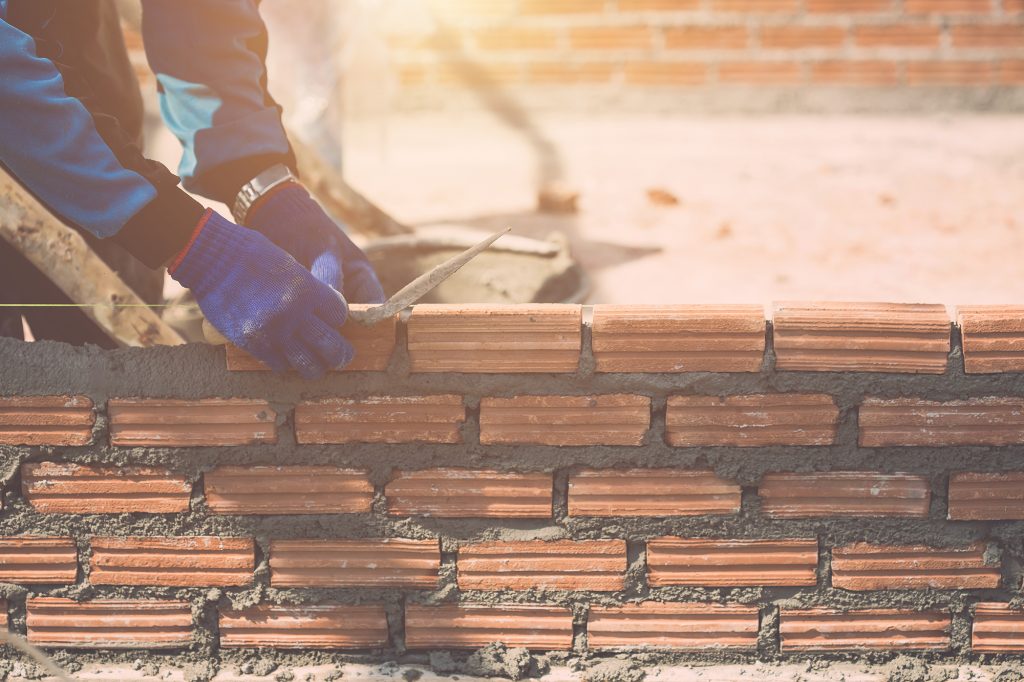 Construction worker installing bricks wall in process of house building