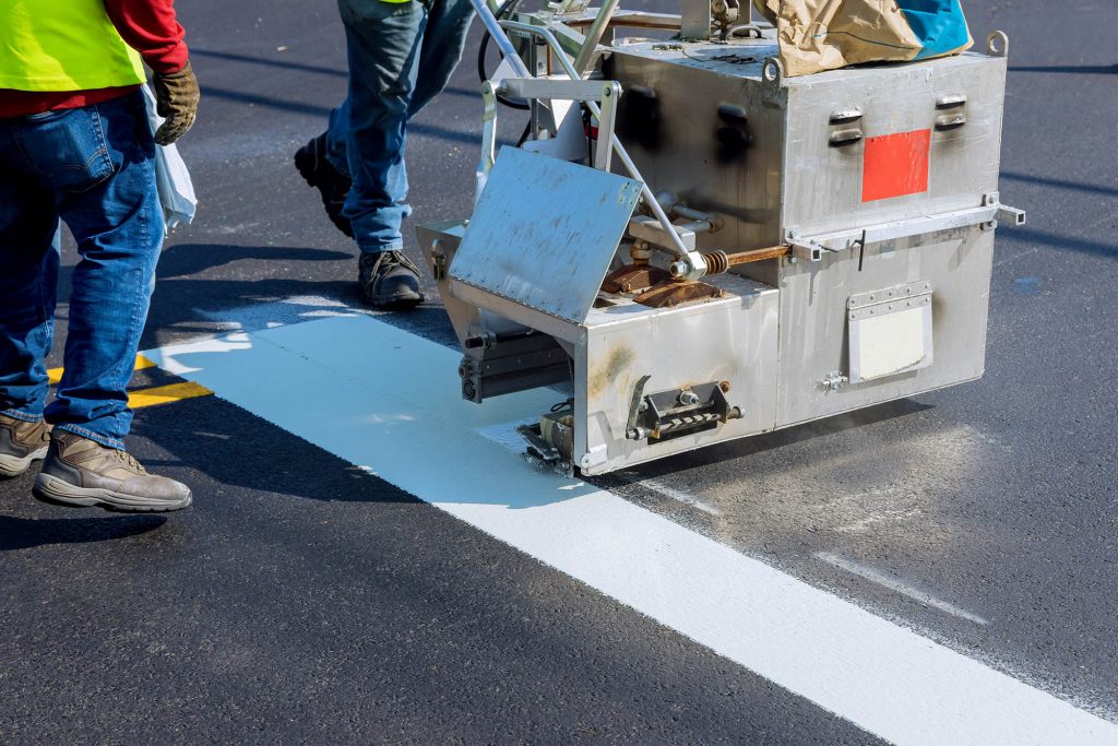 Road worker paint new road surface stripes on new asphalt.